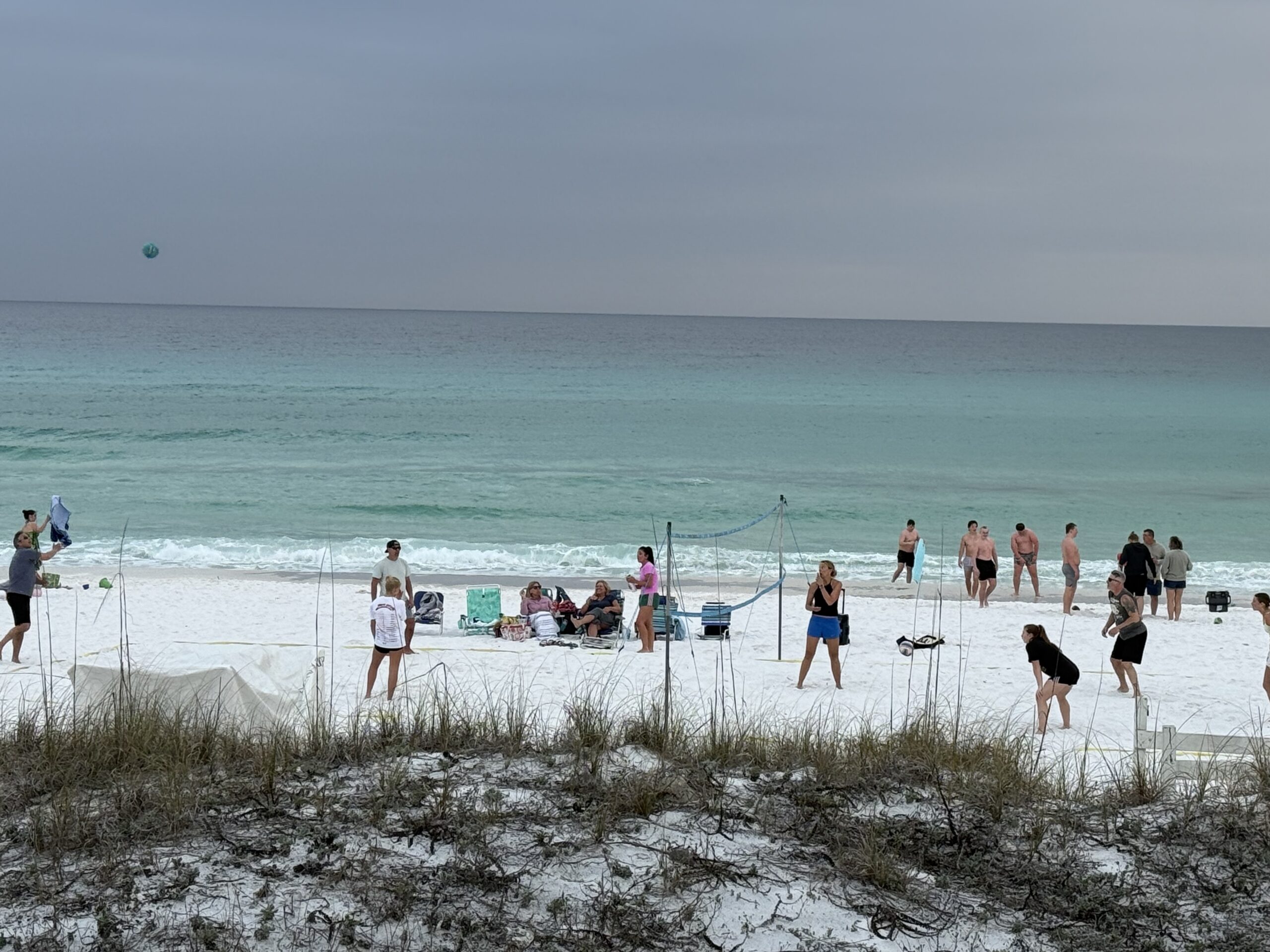 People playing volleyball on the white sand at Miramar Beach, Florida, with turquoise Gulf water
